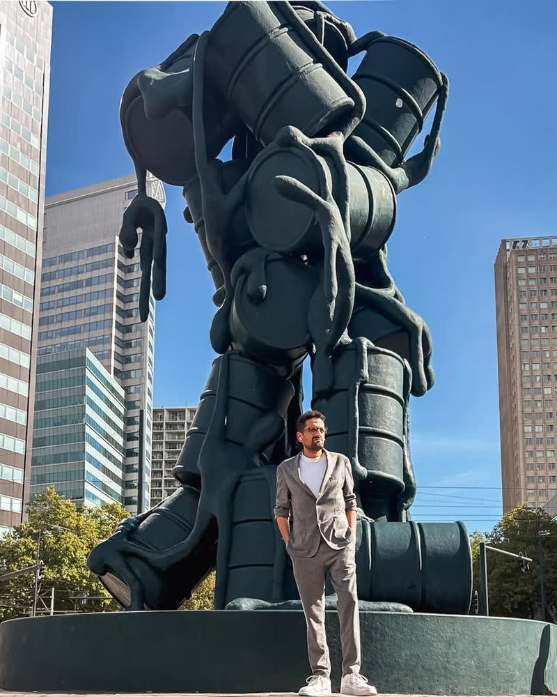 David Omisi standing in front of a large sculpture in Rotterdam
